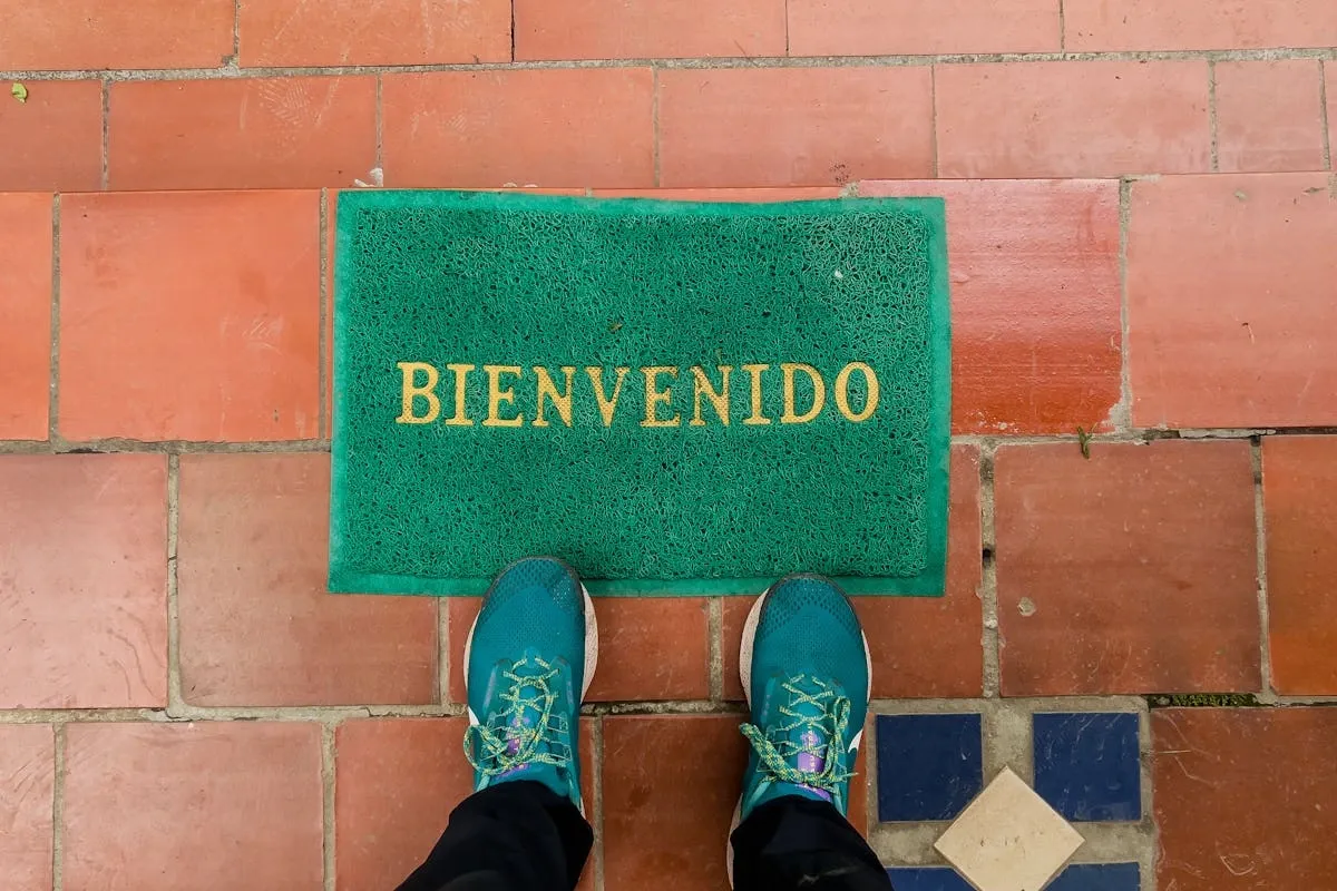 Person standing on Spanish welcome mat that says 'BIENVENIDO' representing Spanish language learning journey