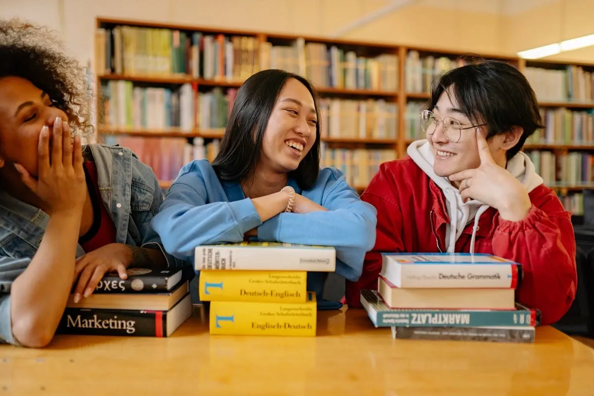 "Diverse group of students studying together with German-English language learning books and dictionaries in library"