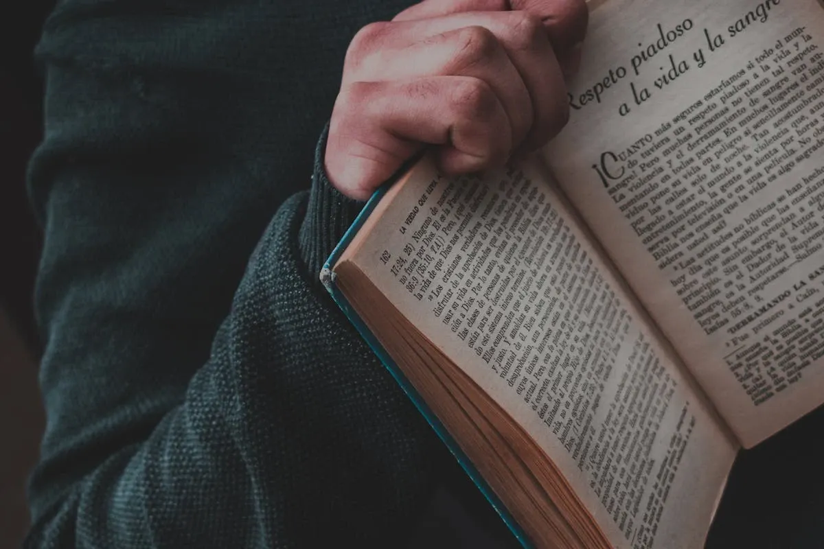 Hands holding open Spanish book or dictionary showing text pages for language study and reading practice
